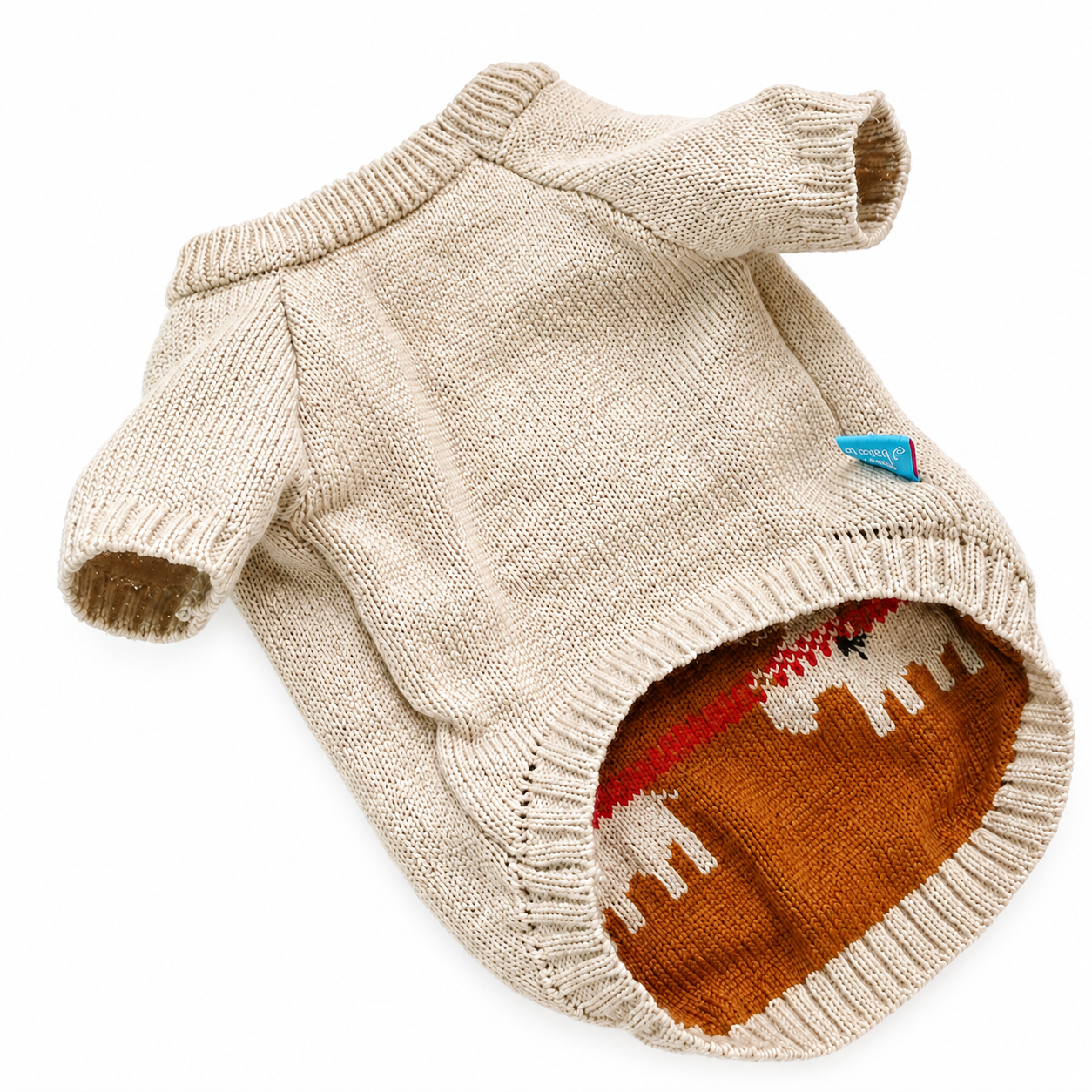 A beige knit pet sweater with long sleeves and a ribbed collar, cuffs, and hem, shown on a white background. The inside of the collar features a brown knit lining with a white reindeer pattern and a small blue tag.