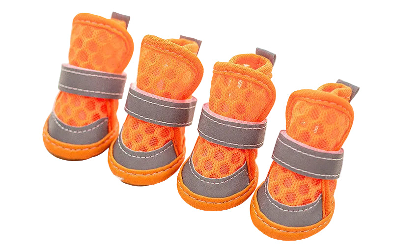 Four orange pet boots with gray straps on a light wooden surface