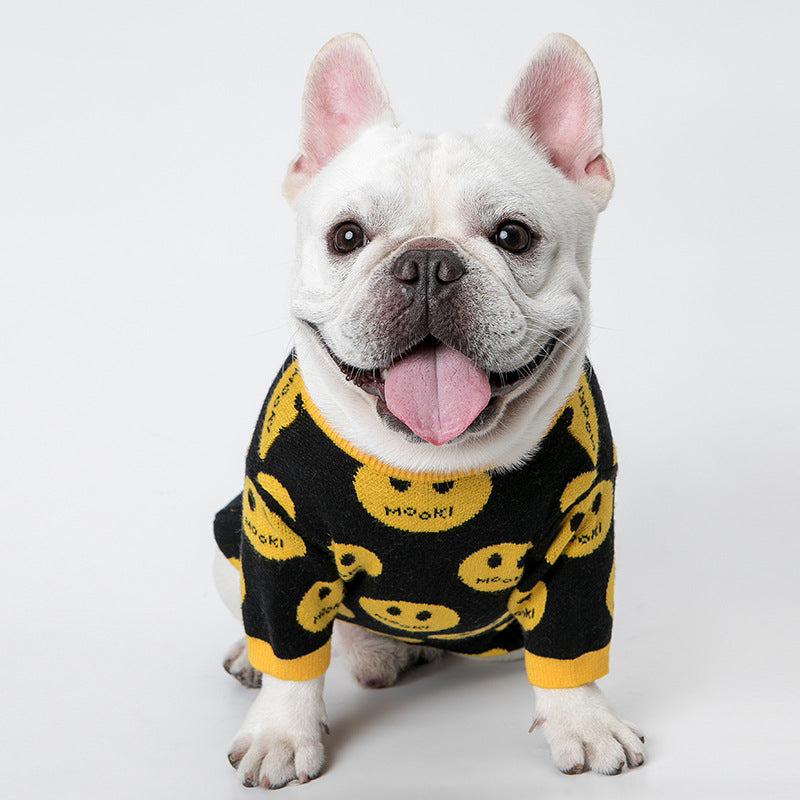 White dog wearing a black outfit with yellow smiley face patterns on a white background